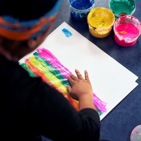trainee child counsellor experimenting finger painting on paper with brightly coloured paints