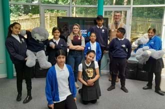 A group of 7 school pupils standing and smiling at the camera, standing with Ben Shires and Kia Pegg, as part of the BAFTA Roadshow