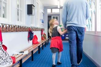 A child holding hands with and looking up to an adult
