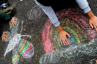 A rainbow and butterfly chalk drawing, with children's hands partially covering the pictures. 