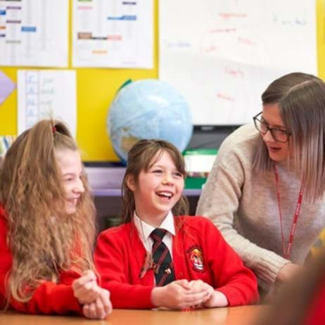 teacher talking to two young people in school classroom