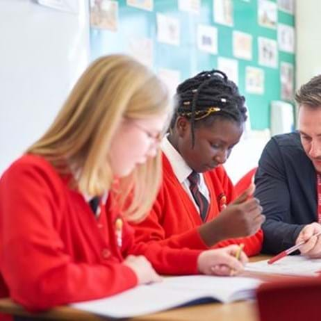 teacher talking to two young people in school classroom